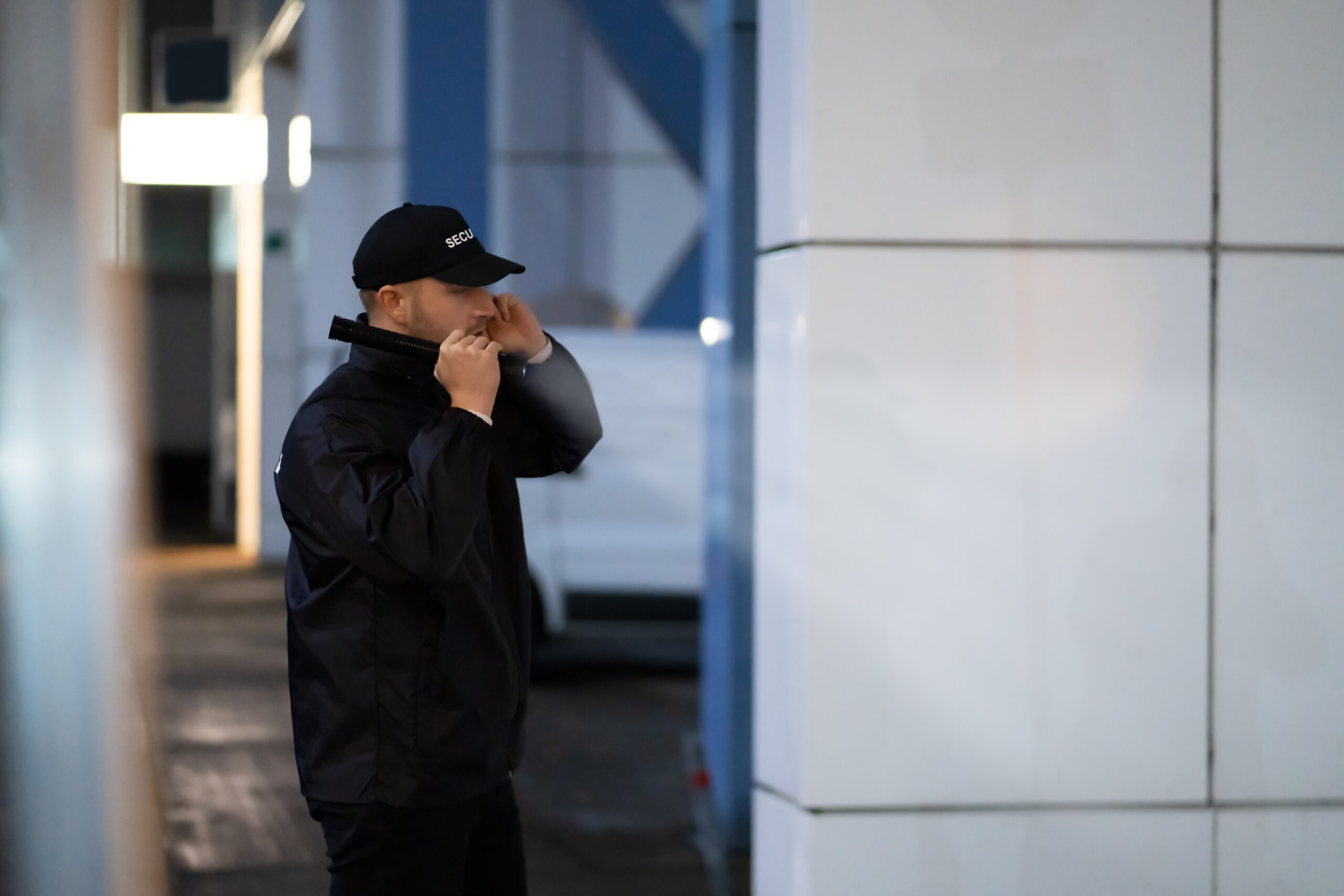 Security Guard Walking Building Perimeter With Flashlight At Night